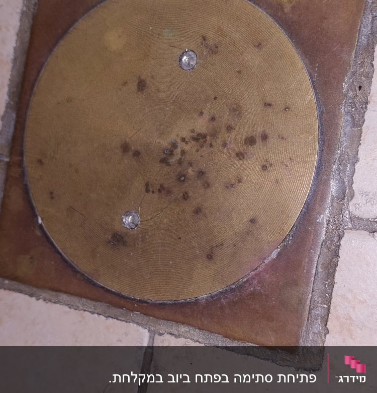 פתח ניקוז עגול ברצפה עם כתמים